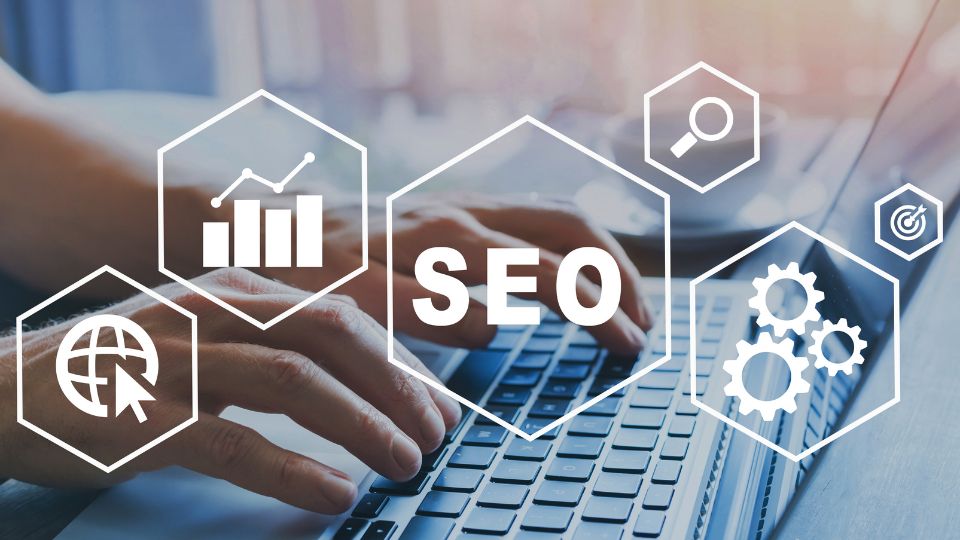 Egy felhasználó keze a laptop billentyűzetén, SEO ikonokkal körülvéve.