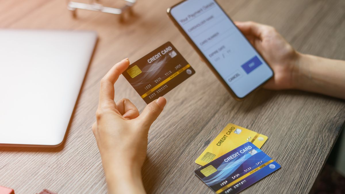 Egy kéz hitelkártyát tart, míg a másik telefonon tranzakciót indít.