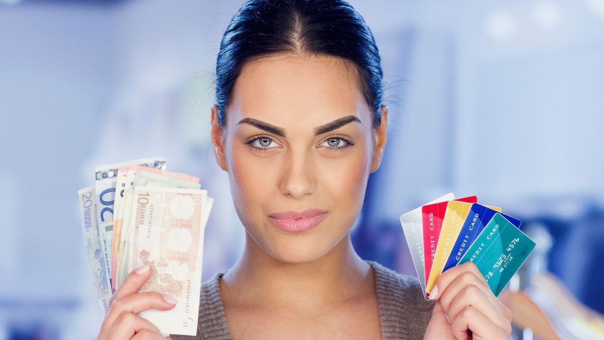 Egy nő készpénzt és bankkártyákat tart a kezében, bemutatva a fizetési lehetőségeket.