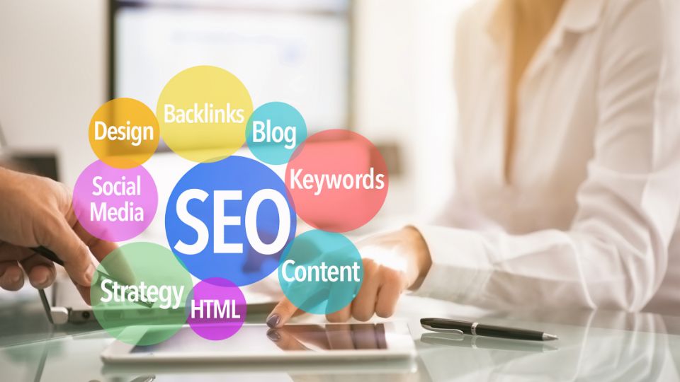 Két ember keze egy asztalon, SEO kulcsszavakkal körülvéve, mint a tartalom és a backlinkek.