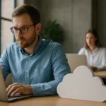 Férfi dolgozik laptopján, háttérben nő, felhőszolgáltatás szimbólum.