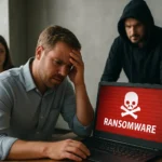 Férfi aggódik a ransomware támadás miatt, miközben két ember figyeli.