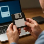 Férfi tart egy floppy lemezt laptop előtt, boot disk jelentősége.