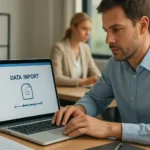 Férfi adatimportálás közben számítógépen, háttérben egy nő.